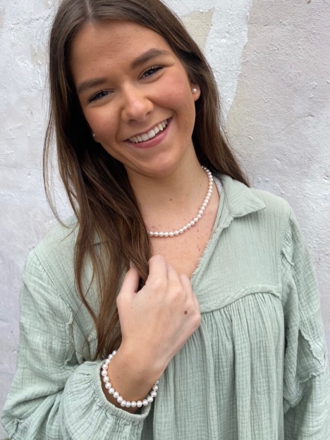 Stephanie smiles as she models a pearl necklace, pearl bracelet, and pearl earrings